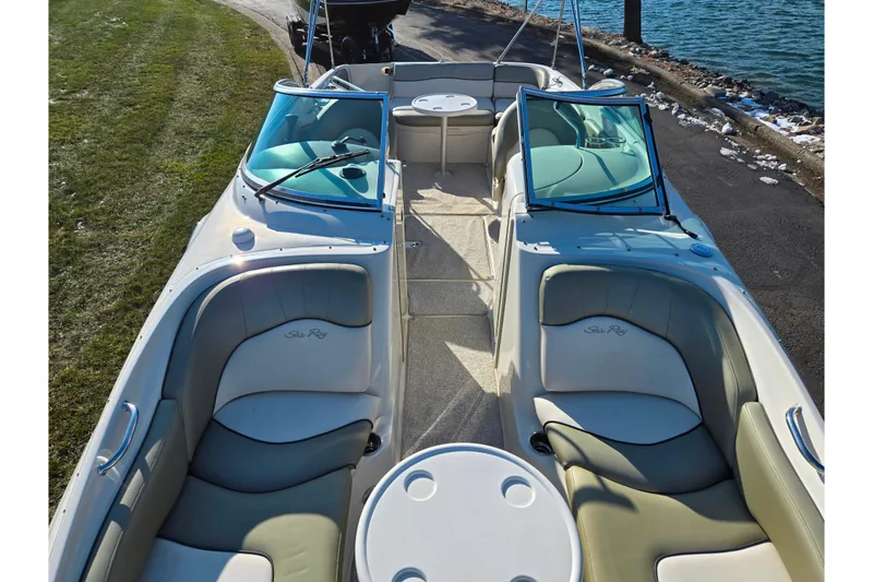 Slide: The Image of 2005 Sea Ray 240 Sundeck boat with spacious seating and table, docked by the water. - 20