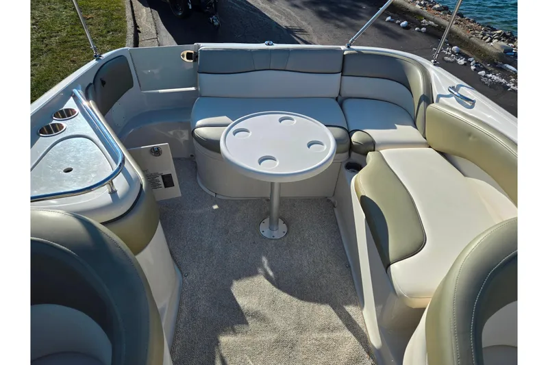 Slide: The Image of 2005 Sea Ray 240 Sundeck interior with seating and table, docked by the water. - 22