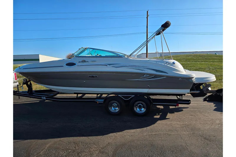 Slide: The Image of 2005 Sea Ray 240 Sundeck boat on trailer, parked outdoors under clear blue sky. - 4