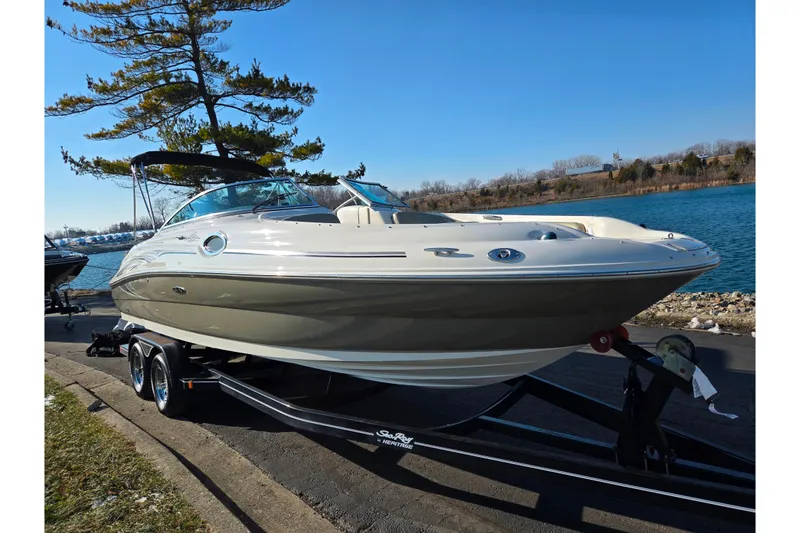 Slide: The Image of 2005 Sea Ray 240 Sundeck boat on trailer by a lakeside under clear blue sky. - 8