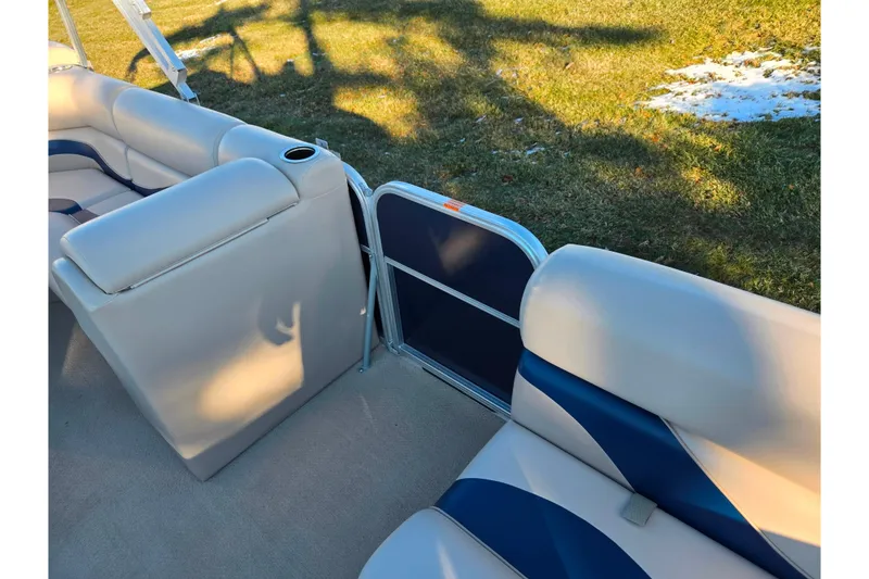 Slide: The Image of 2012 Berkshire 190CL LSR boat interior with beige and blue seating, cup holder, and grassy background. - 11