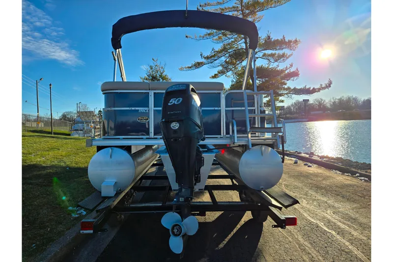 Slide: The Image of 2012 Berkshire 190CL LSR pontoon boat with outboard motor, parked by a sunny lakeside. - 2