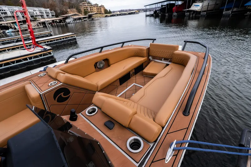 Slide: The Image of Luxurious Anthem Assault ST23 boat interior with tan seating, docked by a serene waterfront. - 12