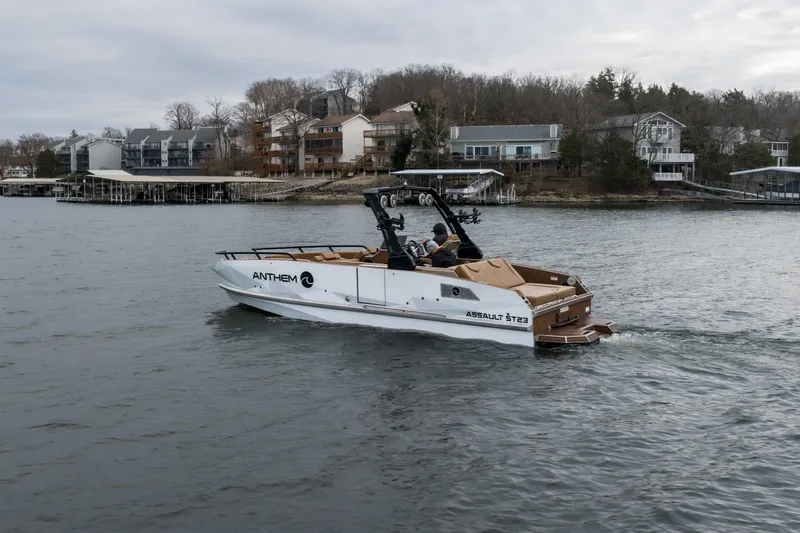Slide: The Image of 2026 Anthem Assault ST23 boat cruising on a lake near waterfront homes. - 32