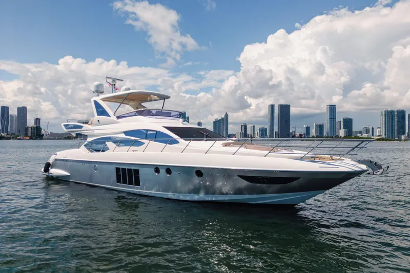 The Image of 2016 Azimut 64 Flybridge yacht cruising near city skyline under blue sky. - 0