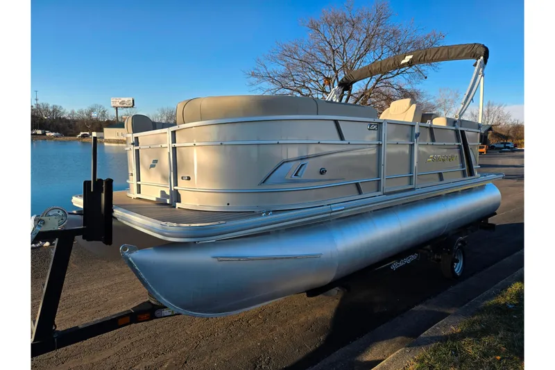 Slide: The Image of 2021 Starcraft EX 20 R pontoon boat on trailer by a lake. - 8