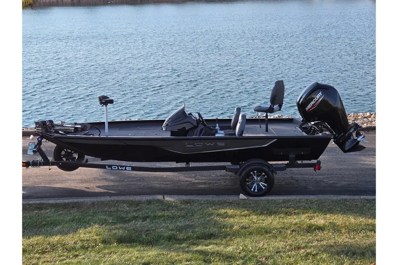 The Image of 2023 Lowe Stinger 175C fishing boat by a lake, featuring a Mercury outboard motor. - 0