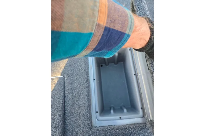 Slide: The Image of 2023 Lowe Stinger 175C boat storage compartment with person opening lid. - 23
