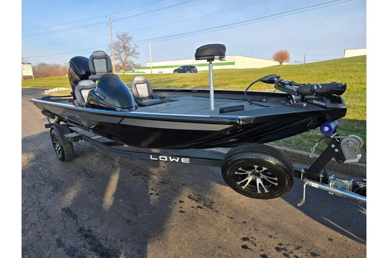 Slide: The Image of 2023 Lowe Stinger 175C fishing boat on trailer, black exterior, parked outdoors. - 5