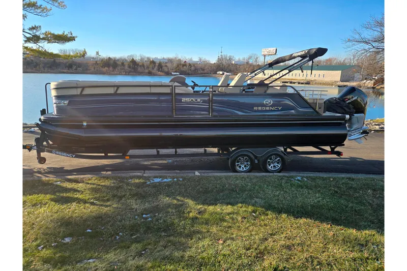 Slide: The Image of 2024 Regency 250 LE3 Sport pontoon boat on trailer by a lake. - 10