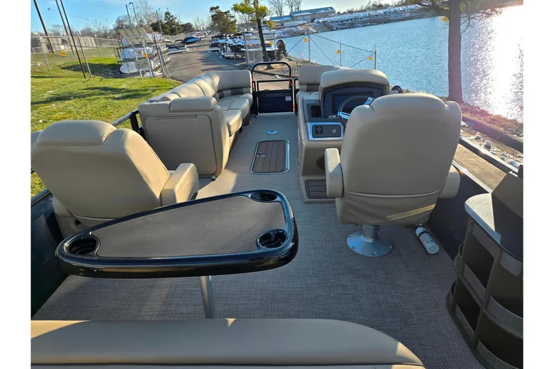 Slide: The Image of 2024 Regency 250 LE3 Sport pontoon boat interior with beige seating and lake view. - 19