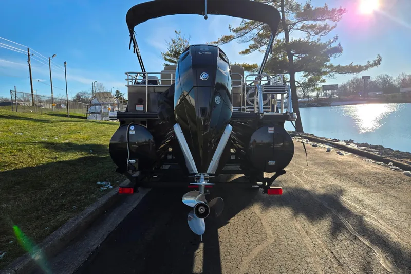 Slide: The Image of 2024 Regency 250 LE3 Sport boat parked by a serene lakeside under a clear blue sky. - 2