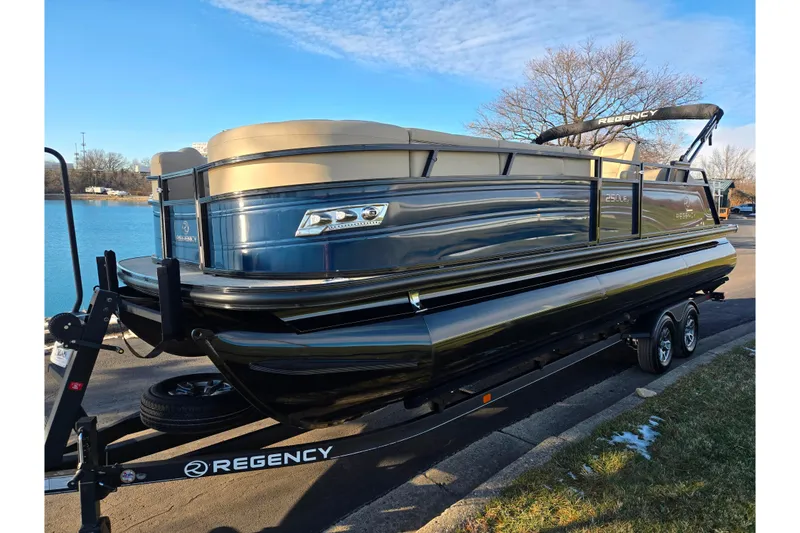 Slide: The Image of 2024 Regency 250 LE3 Sport pontoon boat on trailer by a lake. - 9