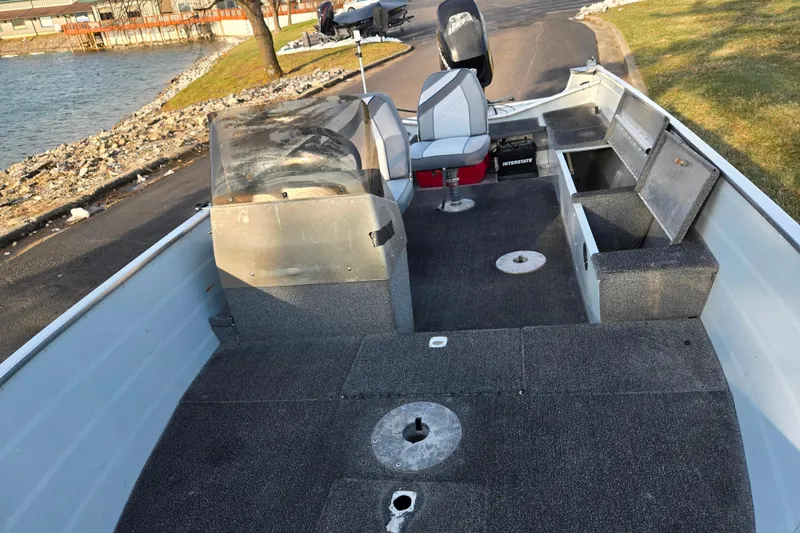 Slide: The Image of 1994 Tracker Pro Deep V-16 boat interior with seating and storage, near a lakeside. - 12
