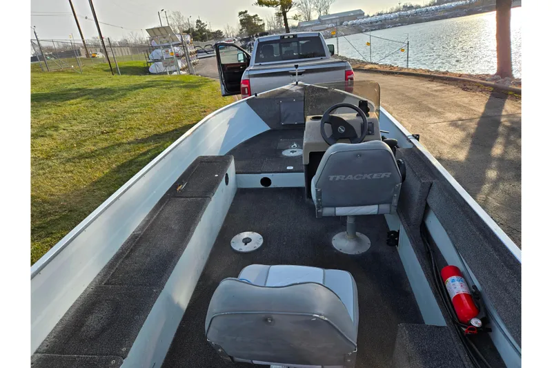 Slide: The Image of 1994 Tracker Pro Deep V-16 boat interior with steering wheel, seats, and fire extinguisher by a lake. - 16