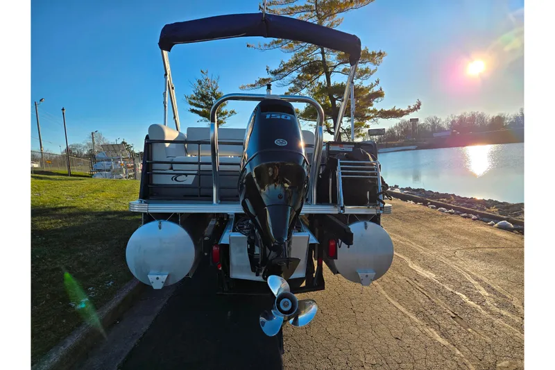 Slide: The Image of 2022 Crest Classic LX 220 pontoon boat by a serene lake at sunset. - 2