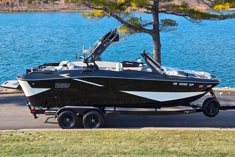 The Image of 2023 Heyday H22 boat on trailer by a lake, showcasing sleek black and white design. - 0