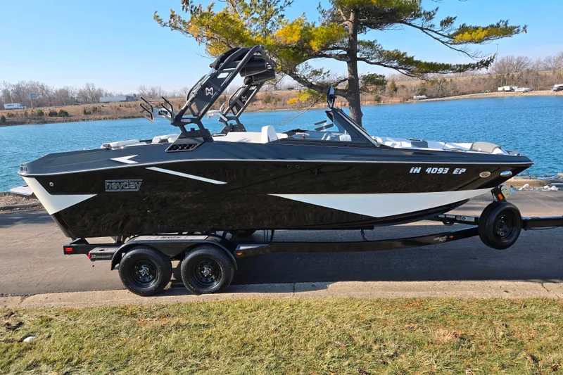 Slide: The Image of 2023 Heyday H22 boat on trailer by a lake, featuring sleek black and white design. - 9