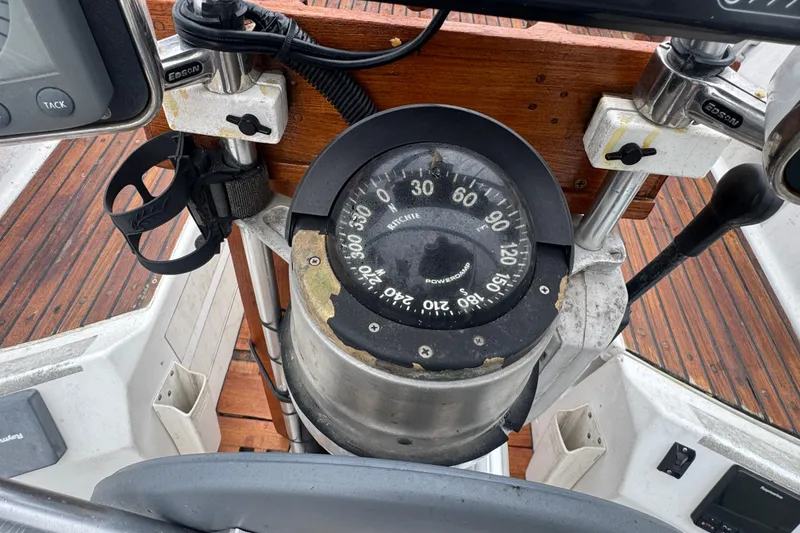 Slide: The Image of Compass on 1985 Beneteau First 38 sailboat, wooden deck background. - 12