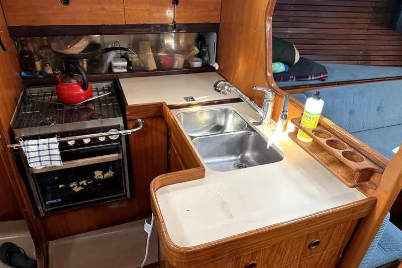 Slide: The Image of 1985 Beneteau First 38 yacht kitchen with stove, sink, and wooden cabinetry. - 18