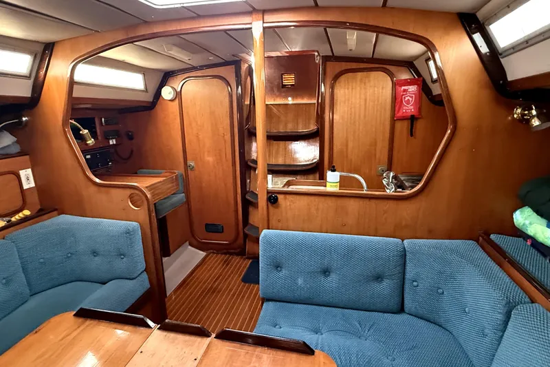 Slide: The Image of Interior of 1985 Beneteau First 38 sailboat with wood paneling and blue seating. - 24