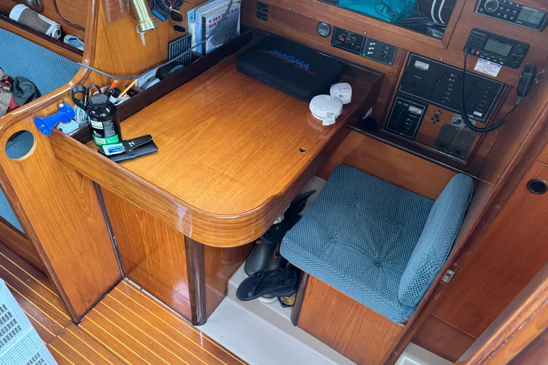 Slide: The Image of Navigation station inside a 1985 Beneteau First 38 sailboat, featuring wooden desk and blue cushioned seat. - 28