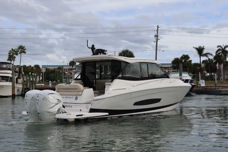 Slide: The Image of 2022 Regal 36 XO boat docked in marina, front view with palm trees in background. - 6