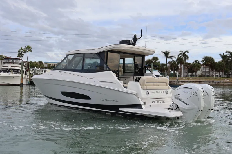Slide: The Image of 2022 Regal 36 XO boat cruising in a marina with twin Yamaha engines. - 7