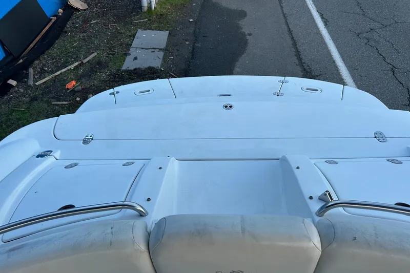 Slide: The Image of 2003 Four Winns 225 Sundowner boat deck, white with metal railings, parked roadside. - 15