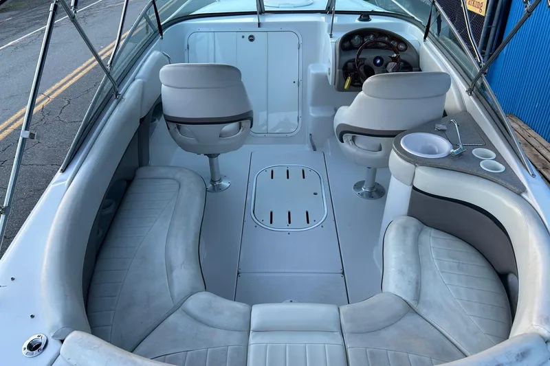 Slide: The Image of 2003 Four Winns 225 Sundowner boat interior with seating, steering wheel, and sink. - 18