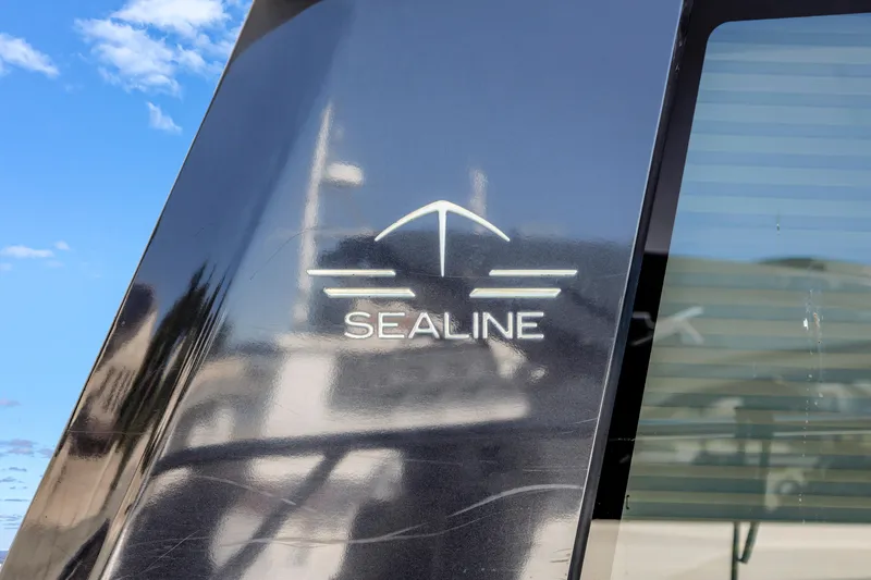Slide: The Image of Sealine C390 2020 yacht logo on sleek black surface with blue sky background. - 20