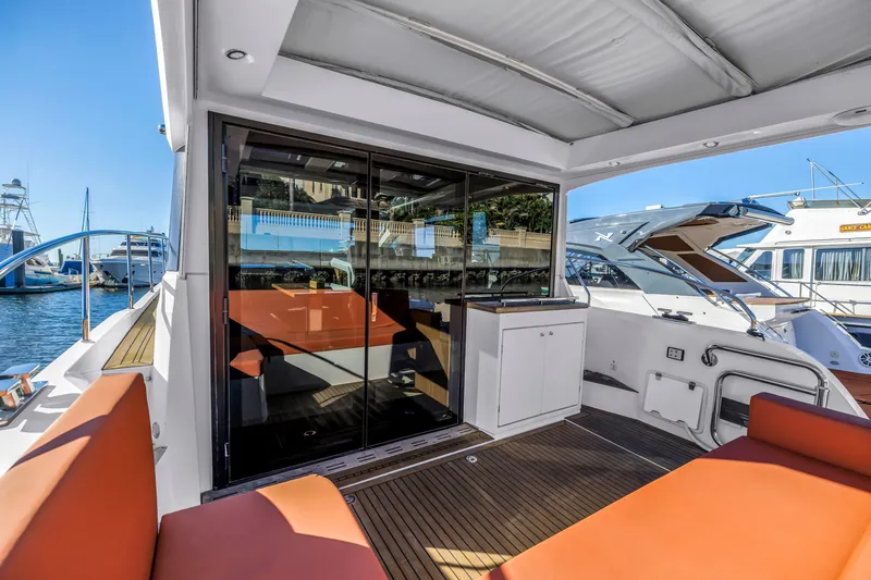 Slide: The Image of 2020 Sealine C390 yacht with spacious deck, orange seating, and modern design in marina setting. - 22