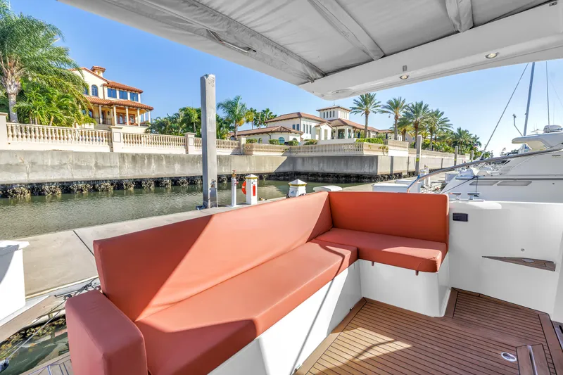 Slide: The Image of 2020 Sealine C390 yacht with red seating, docked near luxury waterfront homes. - 25