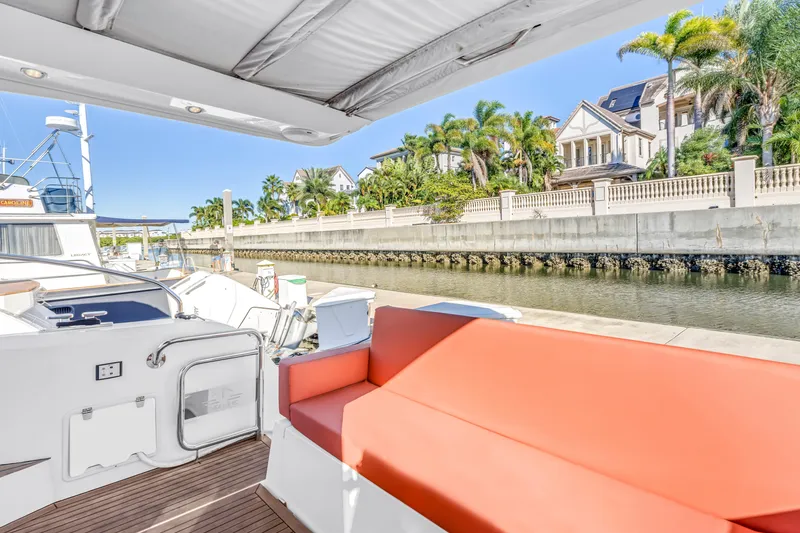 Slide: The Image of 2020 Sealine C390 yacht with red seating, docked near waterfront homes and palm trees. - 26