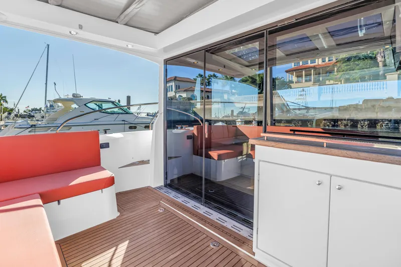 Slide: The Image of 2020 Sealine C390 yacht interior with red seating and wooden flooring at a marina. - 27