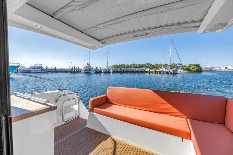 Slide: The Image of 2020 Sealine C390 yacht with orange seating, docked at a marina under clear blue skies. - 28