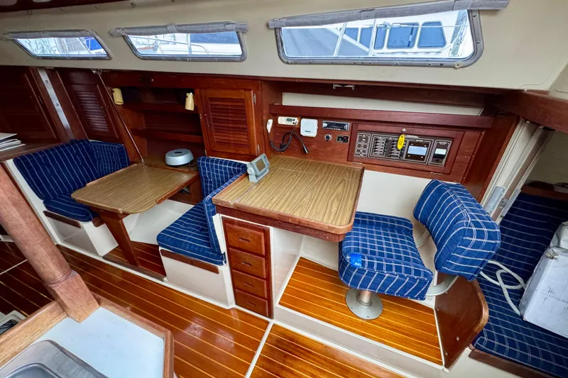 Slide: The Image of 1986 Catalina 36 yacht interior with wood finish, blue plaid seating, and navigation station. - 6