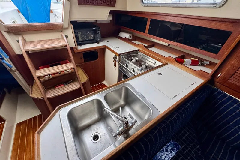 Slide: The Image of Interior of 1986 Catalina 36 sailboat kitchen with sink, stove, and wooden cabinetry. - 8