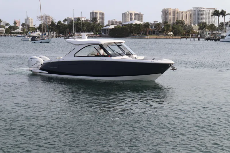Slide: The Image of 2022 Regal LX36 boat cruising on calm waters near a city skyline. - 1