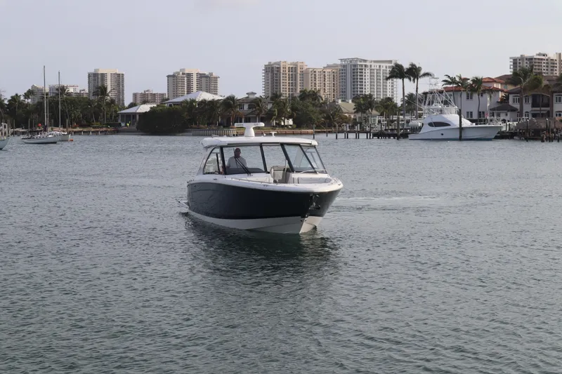 Slide: The Image of 2022 Regal LX36 boat cruising in a coastal city harbor with buildings in the background. - 13