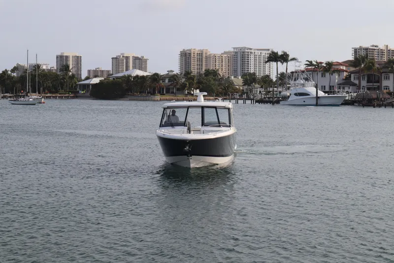 Slide: The Image of 2022 Regal LX36 boat cruising in a coastal city harbor with buildings in the background. - 16