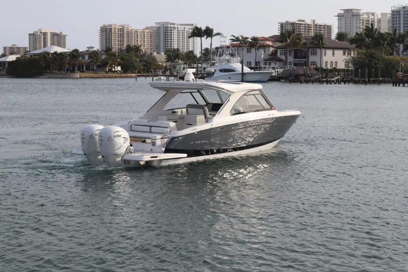 Slide: The Image of 2022 Regal LX36 boat cruising near waterfront homes and city skyline. - 2