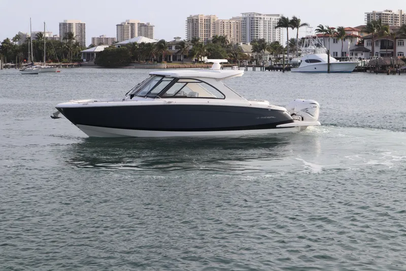 Slide: The Image of 2022 Regal LX36 boat cruising in a scenic waterfront area with city skyline. - 4