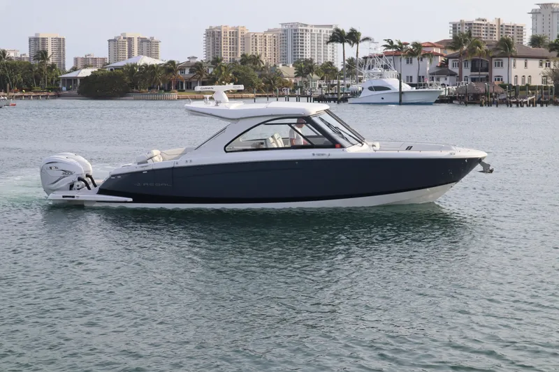 Slide: The Image of 2022 Regal LX36 boat cruising on a calm waterway with cityscape background. - 9