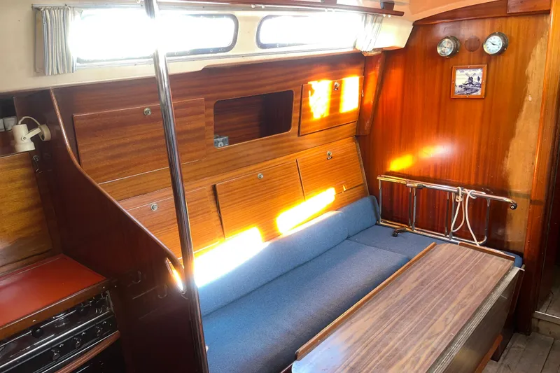 Slide: The Image of Interior of a 1975 Contest 36 sailboat with wooden paneling and blue seating. - 11