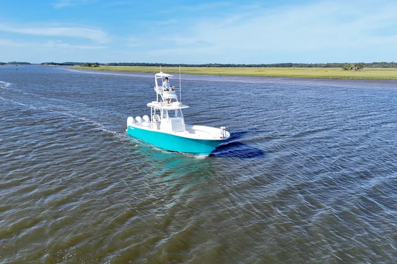 Slide: The Image of 2021 Onslow Bay 33 Tournament boat cruising on a calm river under a clear blue sky. - 47