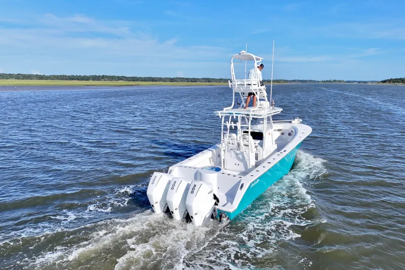 Slide: The Image of 2021 Onslow Bay 33 Tournament boat cruising on open water, featuring triple outboard engines. - 48