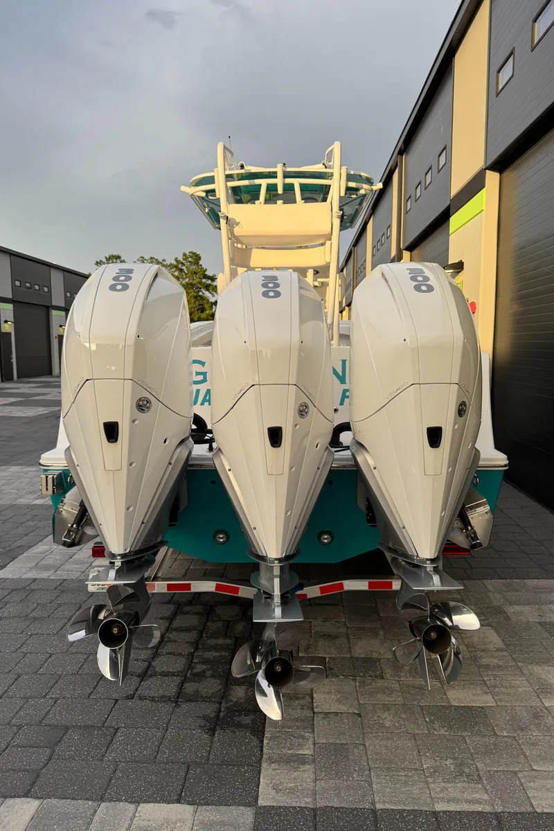 Slide: The Image of 2020 Onslow Bay 33 Tournament boat with triple outboard engines, docked on a paved surface. - 58