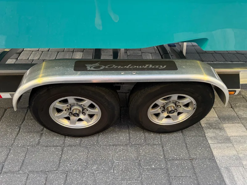 Slide: The Image of Trailer wheels of a 2020 Onslow Bay 33 Tournament boat on pavement. - 62