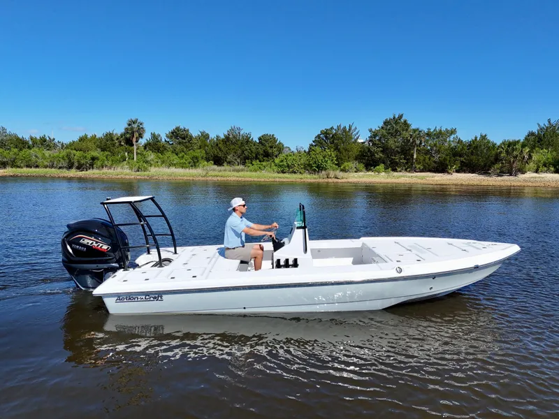 Slide: The Image of 2025 Action Craft 20 Flats boat cruising on a calm river with a clear blue sky. - 11